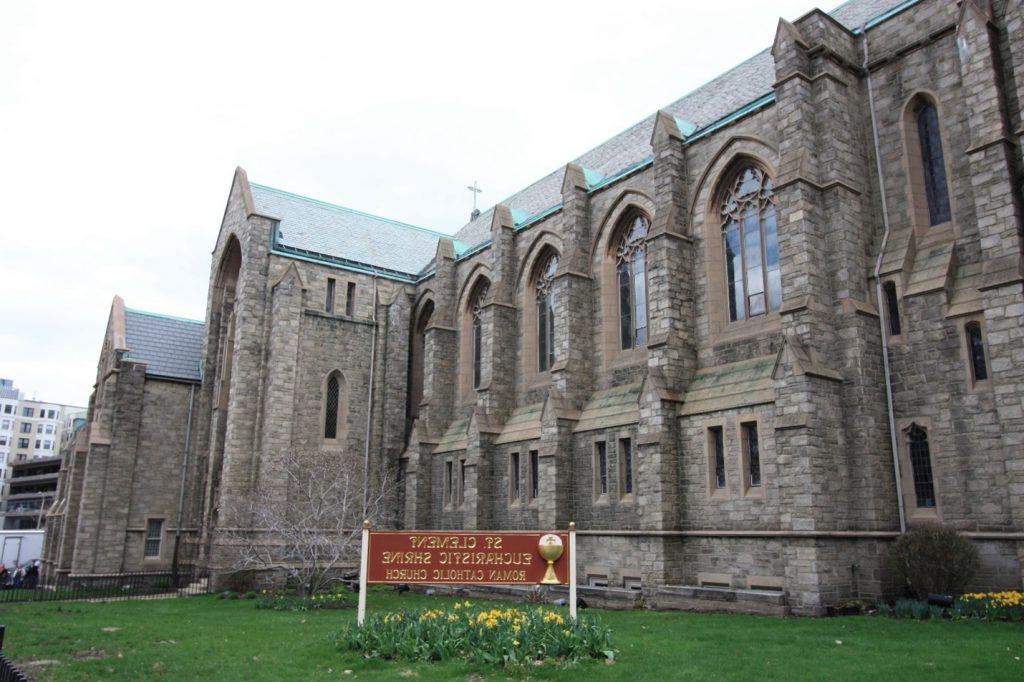 The large gray stone exterior of St. Clement Eucharistic Shrine, with pointed arches throughout.